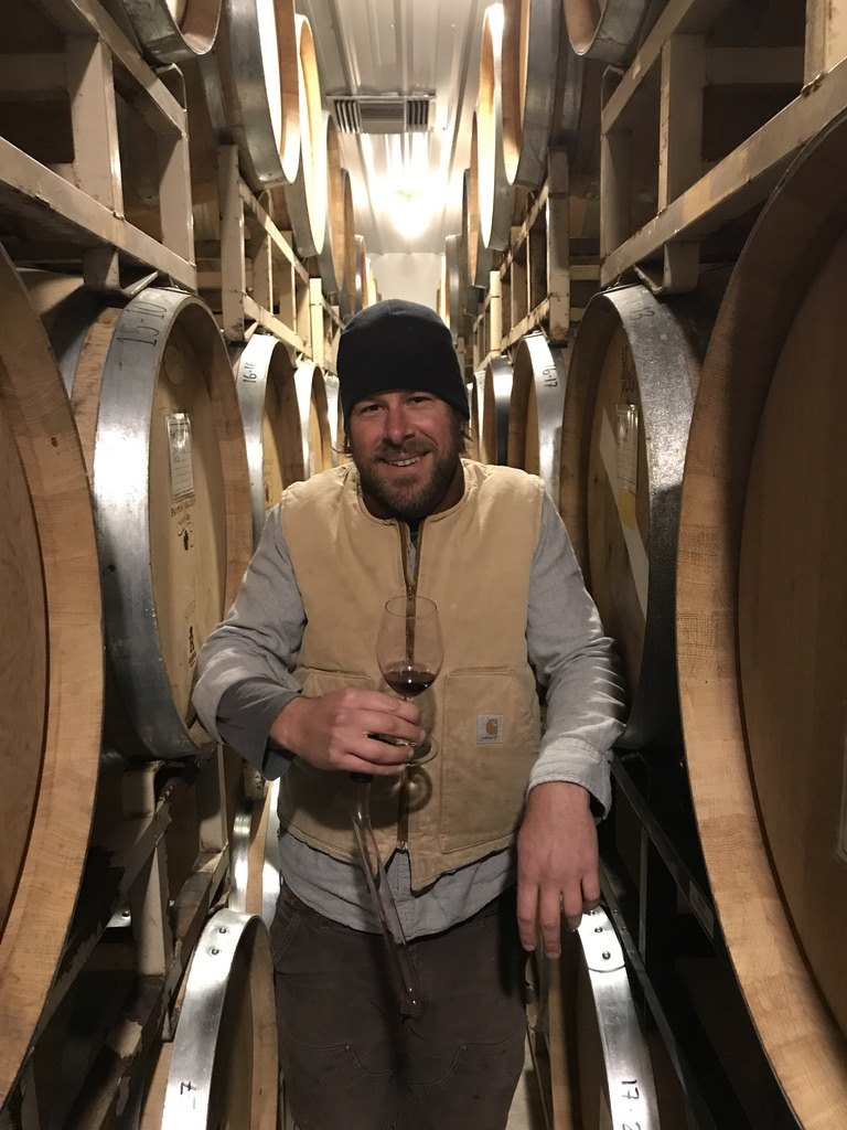 Winemaker Derek Einberger holding a glass of red wine in the barrel room