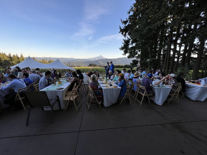 Guests at a long outdoor table with Mt. Hood in the distance